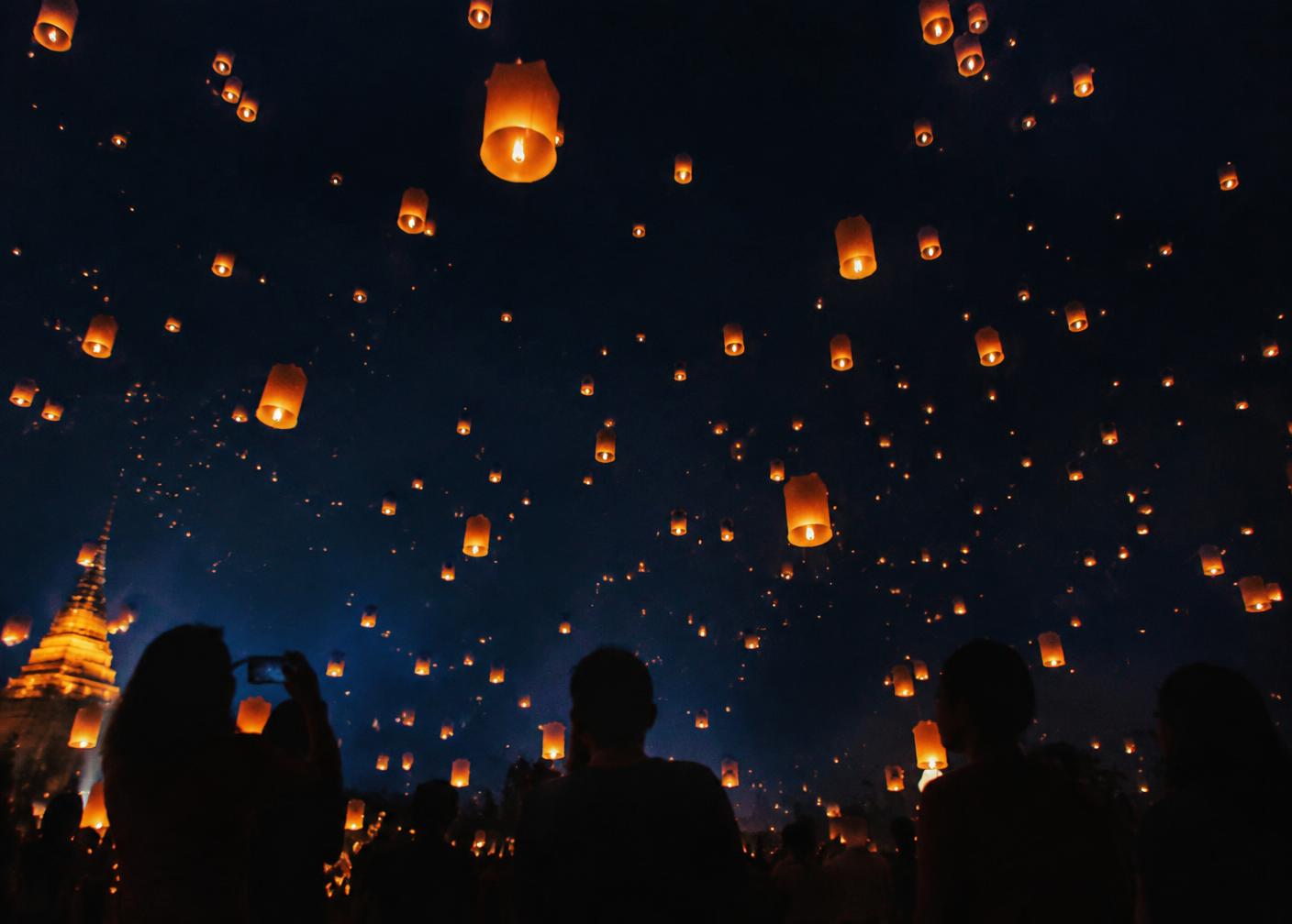 Lanternas iluminadas subindo ao céu noturno durante festival na Tailândia